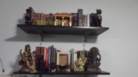 Top shelf has the lararium, and the Bast statues I own. Lower shelf has my dictionaries and related books, my Ganesha and Saraswati statues, and my Earth shrine. Well, what will become the Earth shrine, when I get around to finishing the box.